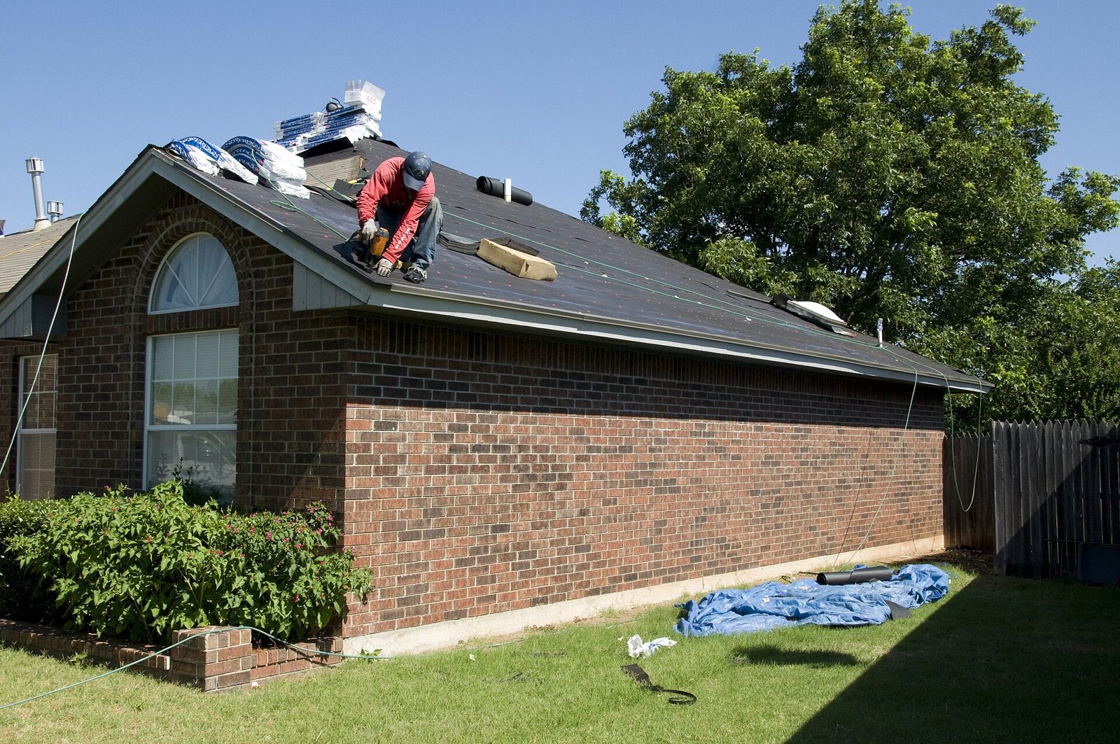 Roofer fitting a new roof covering on a brick bungalow