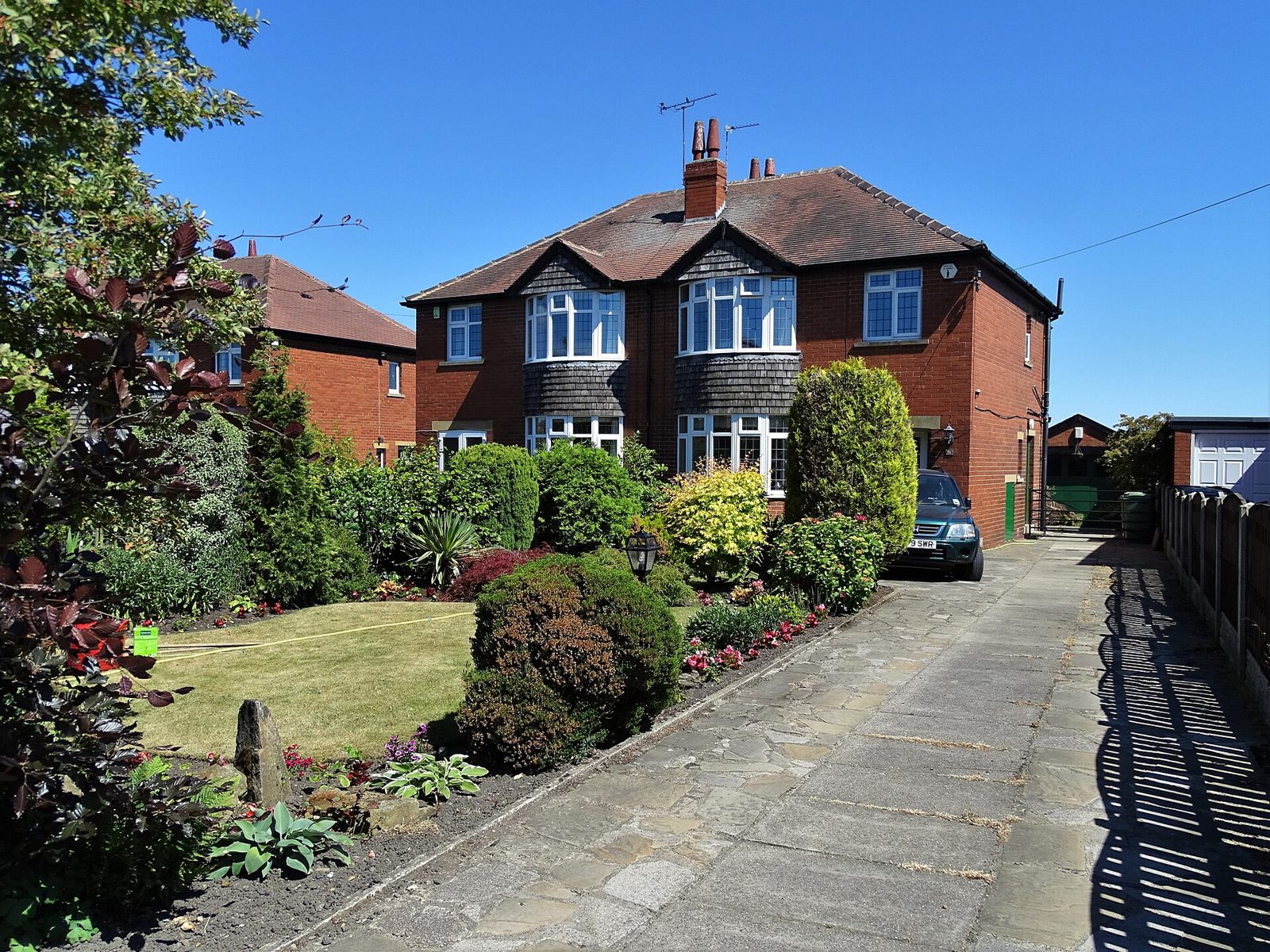 Red-brick semi-detached house with tiled pitched roof and front garden